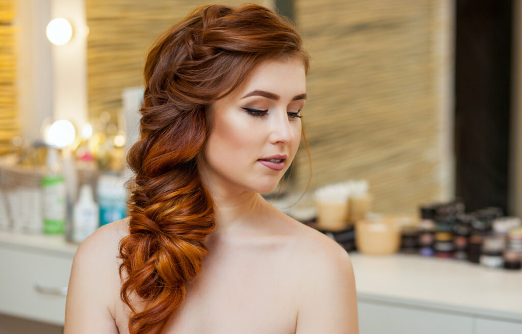 Women with red hair posing in a loose french braid hairstyle